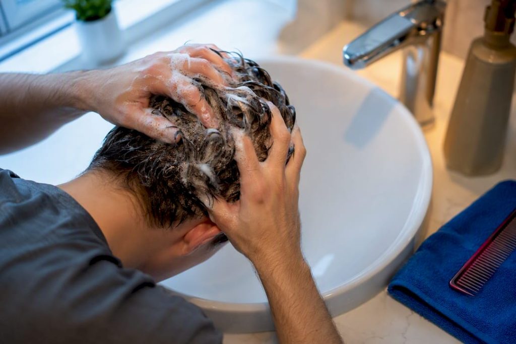 Hands washing hair in clean bathroom